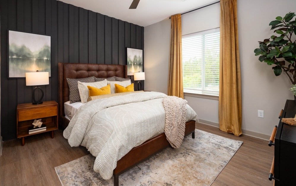 Furnished bedroom with brown accent wall at Ava Oakwood apartments in Gainesville