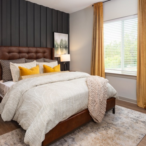 Furnished bedroom with brown accent wall at Ava Oakwood apartments in Gainesville Furnished bedroom with brown accent wall at Ava Oakwood apartments in Gainesville