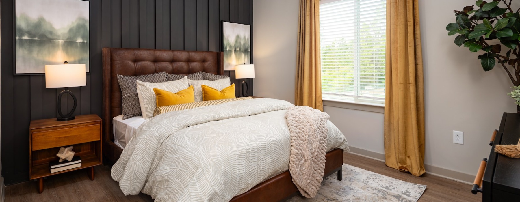 Furnished bedroom with brown accent wall at Ava Oakwood apartments in Gainesville