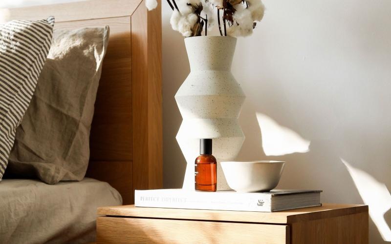 a vase with cotton stems on a bedside table